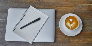 Notebook, pen, and coffee on a wooden table